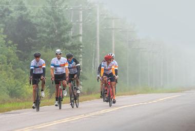 A small group of cyclists riding through rain.