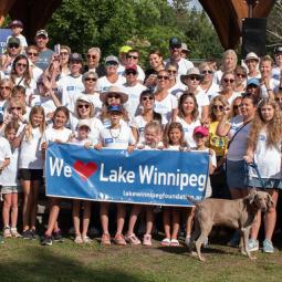 A large group of people in white t-shirts standing in front of a banner